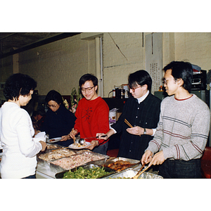 Men and women get food at the buffet table at the Chinese Progressive Association and garment workers' tenth anniversary celebration