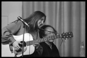 Judy Collins with guitar at the microphone, accompanied by Michael Sahl on piano