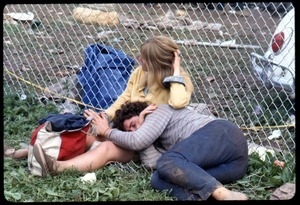 Couple sacked out by a chain link fence at the Woodstock Festival