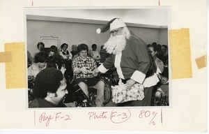 Man dressed as Santa Claus handing out gifts at Christmas party