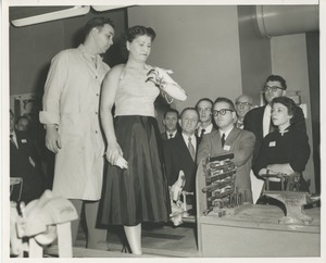 A technician and a patient demonstrate how her prosthetic arm works while a group of men and women look on