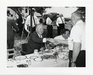 Mayor John F. Collins with an unidentified man at an outdoor luncheon