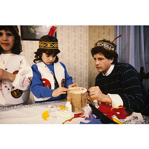 Child being helped with a craft while wearing a feather headband