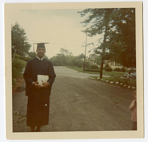 Robert Mello posing in street, in graduation gown