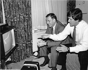 Mayor Raymond L. Flynn watching television while seated on a bed with John Kerry