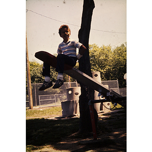 Boy seated on seesaw at a playground