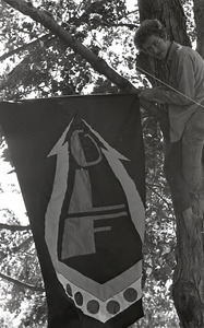 Gay liberation demonstration at Cambridge Common: man hanging Gay Liberation Front flag