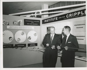 Two unidentified men cutting a ribbon in front of an ICD exhibit