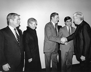 Mayor Raymond L. Flynn shaking hands with Archbishop Bernard F. Law, with others watching