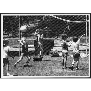 Children playing volleyball outdoors on grass