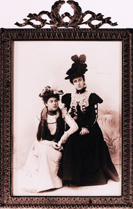 Full-length double portrait of two women, seated, facing front, location unknown
