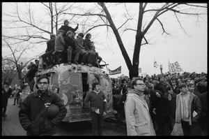Riders piled atop the psychedelic bus 'The Road Trip' parked near anti-war protesters during the Counter-inaugural demonstrations, 1969