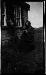 Reuben Austin Snow, the cross-dressing hermit of Cape Cod, knitting in front of house