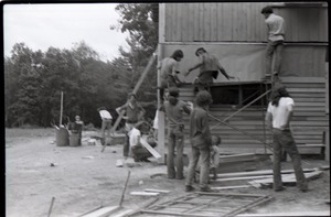 Group putting up clapboards on commune building