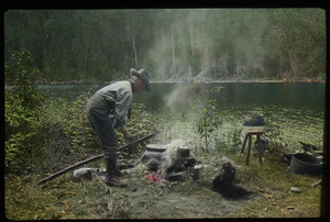 Lake Vassal, Quebec (man tending campfire by lake)