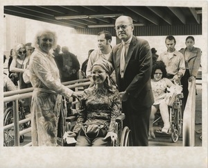 Woman in wheelchair assisted on ramp