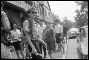 Bob Dylan, with bullwhip and sunglasses, walking on the sidewalk, Newport Folk Festival
