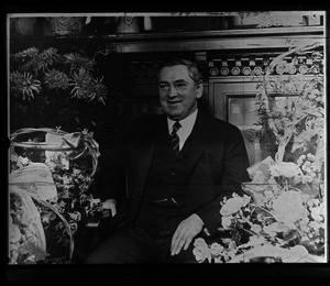 James Michael Curley, seated in front of a fireplace