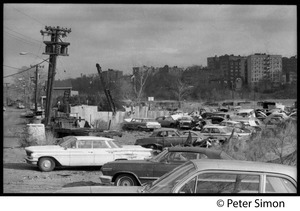 Junked cars with modern apartment buildings in the background