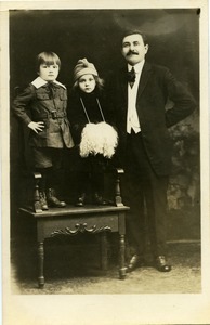 Portrait of unidentified father and children: full-length studio portrait of father, with children standing on studio chair