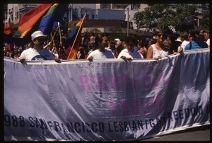 Massive crowd approaching during the San Francisco Pride Parade, with pride flags and banner reading 'Rightfully proud'