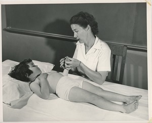 Betty Ann Feinstein holding the hand of a young girl on an exam table