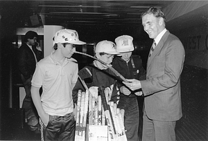 Mayor Raymond L. Flynn looking at Boston Bruin's hockey sticks with three unidentified boys