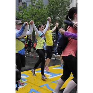 Collection of runners holding hands and embracing at the "One Run" finish line in Copley Square