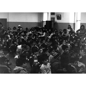 Audience, consisting mostly of Hispanic American children, seated on the floor, watches the Three Kings' Day celebration at La Alianza Hispana