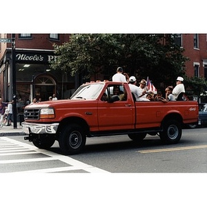 Red pickup truck with men and children in the Festival Betances parade.