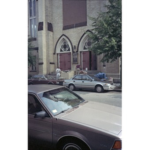 View of the facade of the Jorge Hernandez Cultural Center and two men building a brick divider on the front steps.