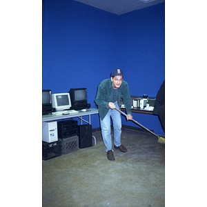 Young man sweeping the floor of a media lab.