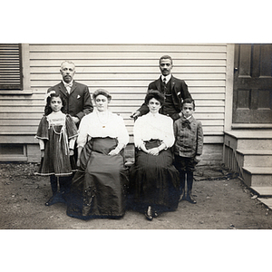 Family portrait, group of six pose in front of house