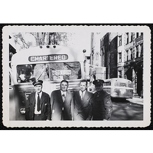 Boys' Club staff members posing in front of a bus while several boys look on from the bus