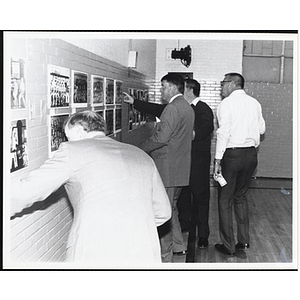 Four men examine photographs on the wall at the South Boston Boys & Girls Club Alumni Party