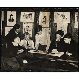 A boy working on a project for his art class while five others look on at the South Boston Boys' Club