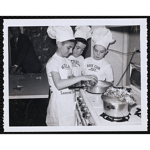 Members of the Tom Pappas Chefs' Club work at a stove in a kitchen