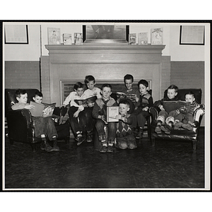 Ten boys seated in front of a fireplace pose holding books