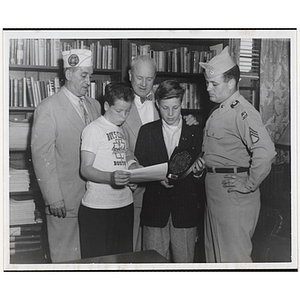 Two boys pose with a plaque and a document along with two veterans and Executive Director Arthur T. Burger (center)