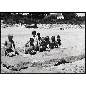A group of children pose in the sand on a beach