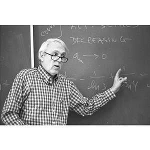 Math professor Bob Case stands at a chalkboard