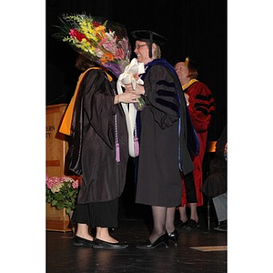 Student presents flowers to School of Nursing faculty member at convocation