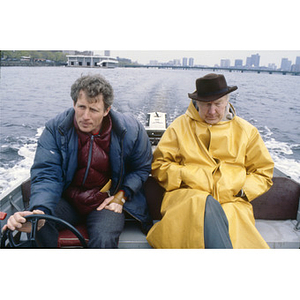 Northeastern men's crew coach Buzz Congram sitting with Brown Coach in a boat