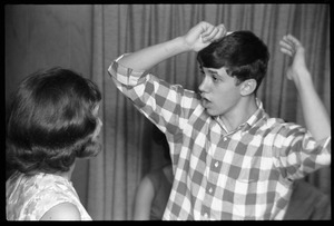 Teenage long hair: boy combing his hair as a girl looks on