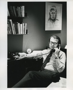William Van den Heuvel seated at desk, on phone