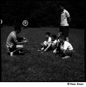 Camp Arcadia: counselor instructing young campers in archery