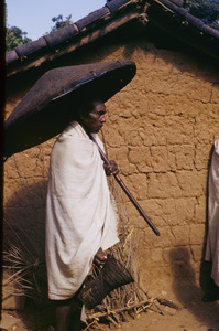 Munda man carrying an umbrella woven from cane or bamboo