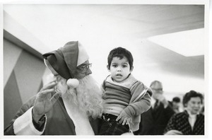 Man dressed as Santa Claus with young boy at Christmas party