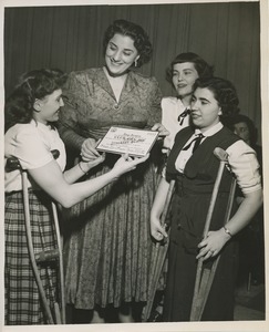 Three young women presenting Kay Armen with a certificate naming her an honorary member of club can do