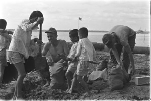 Newly arrived GI's filling sandbags with Vietnamese children at Dong Tam Base; Mekong Delta.